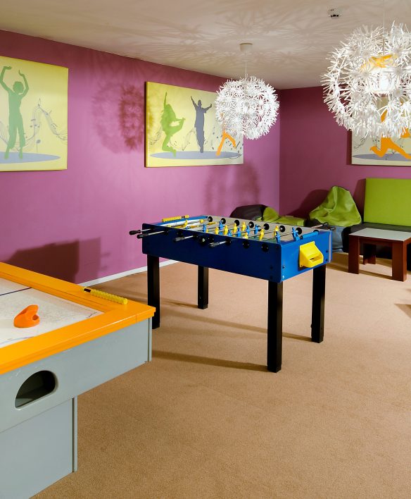 Chill-out-Lounge für größere Kinder in den Kinderwelten des Almhotels Hochhäderich mit Airhockey, Tischfußball und gemütlichen Sitzsäcken in bunten Farben.