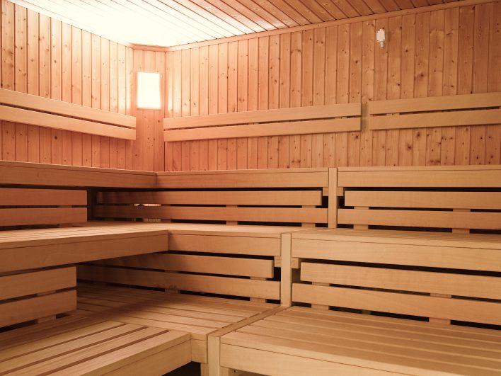Geräumige Sauna im FamSpa mit Holzverkleidung und breiten Liegebänken auf mehreren Ebenen, sanft beleuchtet für einen entspannten Saunagang mit der ganzen Familie.