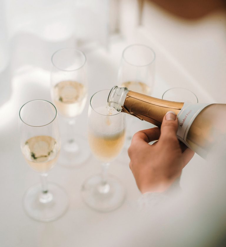 Sekt wird zum Anstoßen in mehrere Sektgläser eingeschenkt.