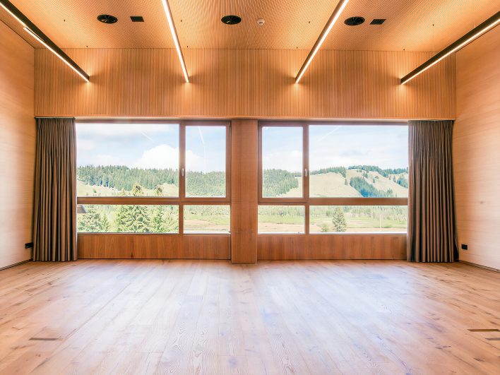 Lichtdurchfluteter Tagungsraum im Almhotel Hochhäderich mit Holzdecke und großen Panoramafenstern mit Blick über Wald und Hochmoor im Bregenzerwald