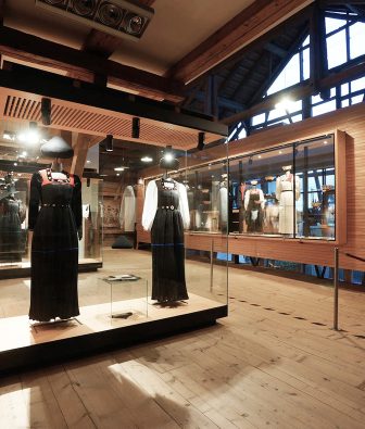 Ausstellung in der Juppenwerkstatt Riefensberg mit der Juppe, der traditionellen Frauentracht des Bregenzerwaldes, in Glasvitrinen unter Holzbalken