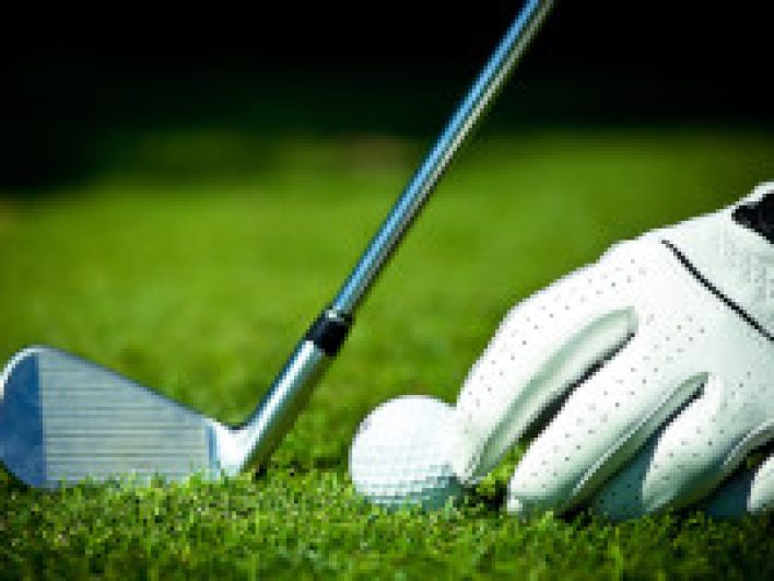 Ein Golfer legt seinen Ball in die Wiese.